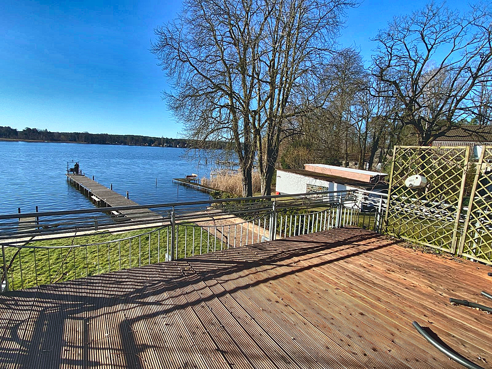 Holzterrasse am Wasser mit Blick auf den privaten Steg und den Krüpelsee