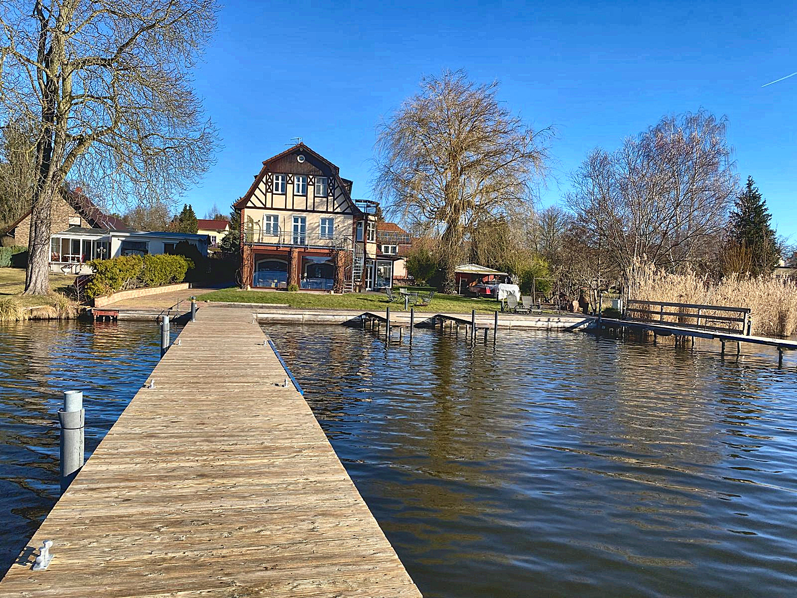 Villa am Krüpelsee in Zernsdorf, vom Steg aus gesehen — der Holzsteg führt über das Wasser direkt auf das Haus zu