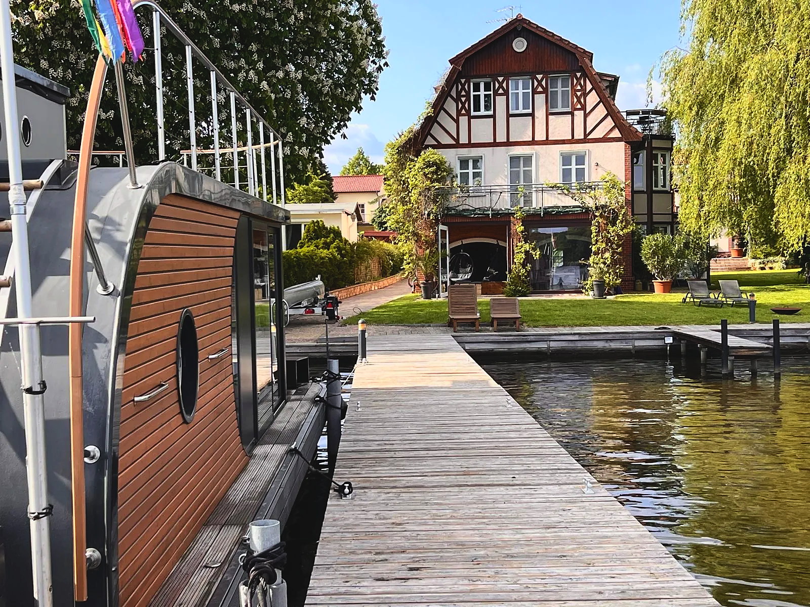 Blick vom privaten Steg auf die Altbauvilla am Krüpelsee in Zernsdorf, mit Hausboot am Ufer und Südausrichtung